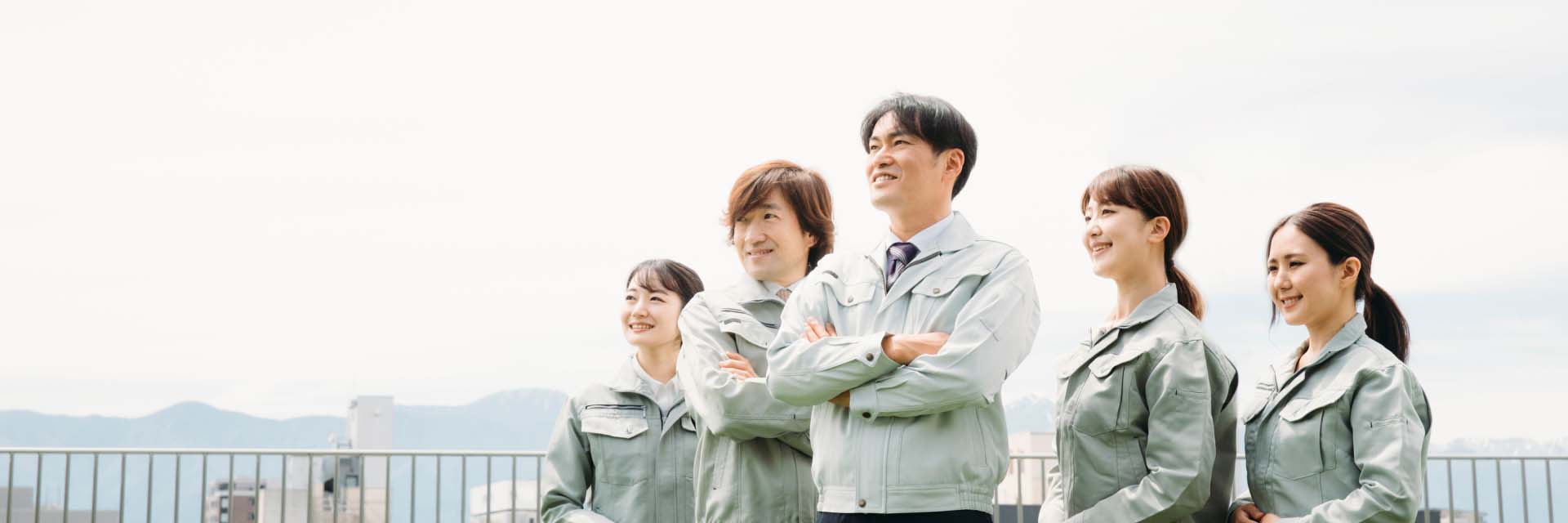 作業服を着た男女が笑顔で空を見上げている様子